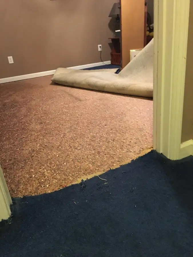 Carpet pad removal revealing water damage during Water Mitigation Services in Leeds